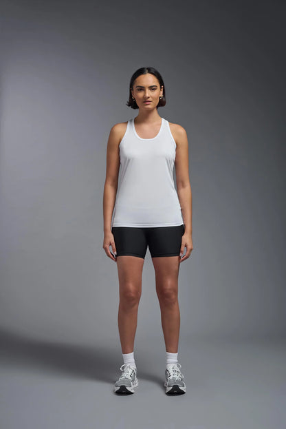 Woman wearing a white tank top and black shorts on a gray background