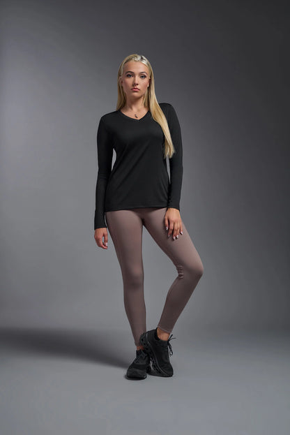 Woman wearing a black long-sleeve top and gray leggings on a gray background