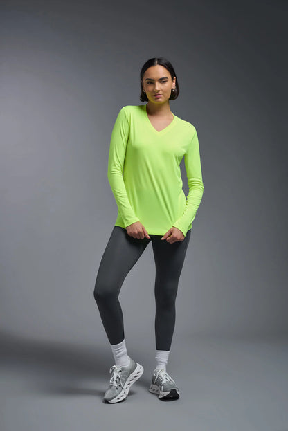 Person wearing a bright green long-sleeve top and black leggings on a gray background