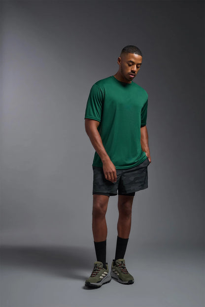 Man wearing a green t-shirt and gray shorts on a gray background
