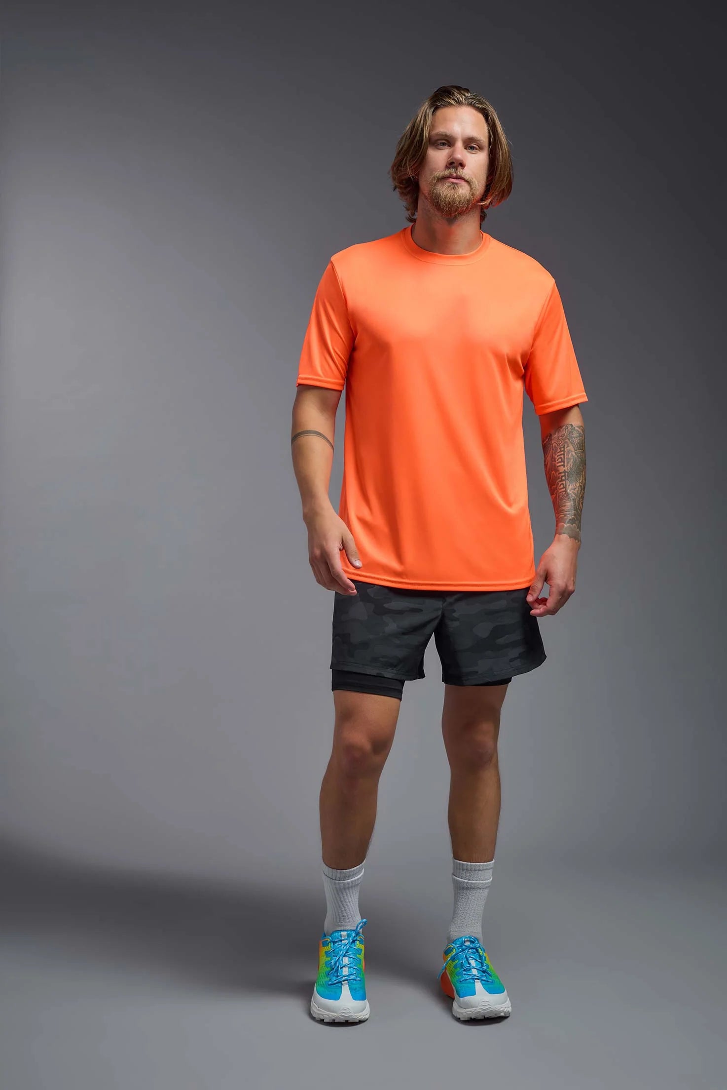 Man wearing an orange t-shirt and black shorts on a gray background