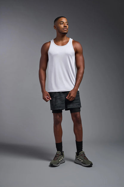 Man wearing a white tank top and black shorts on a gray background