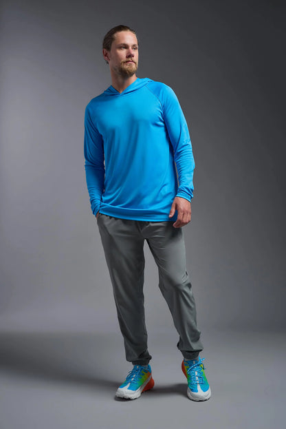 Man wearing a blue long-sleeve shirt, gray pants, and colorful sneakers on a gray background