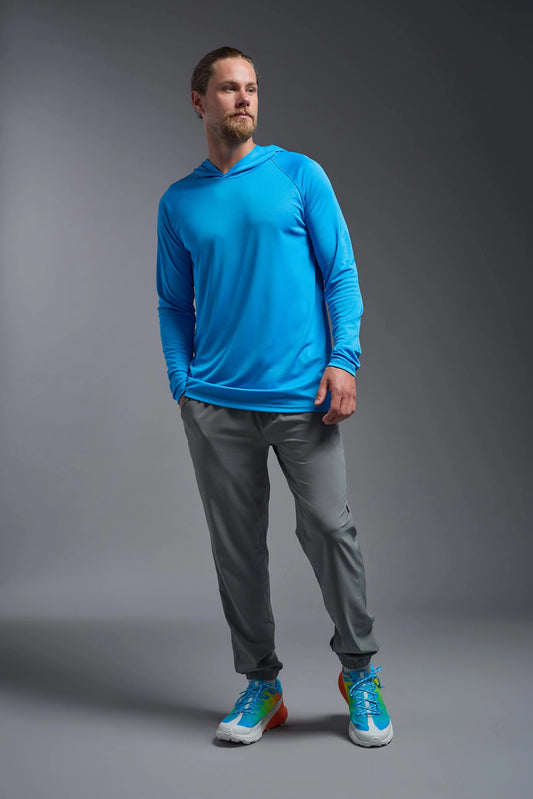 Man wearing a blue long-sleeve shirt, gray pants, and colorful sneakers on a gray background