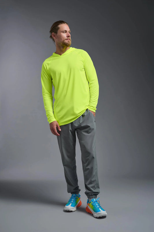 Man wearing a bright green long-sleeve shirt and gray pants on a gray background