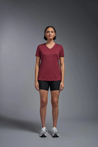 Woman wearing a maroon t-shirt and black shorts against a gray background