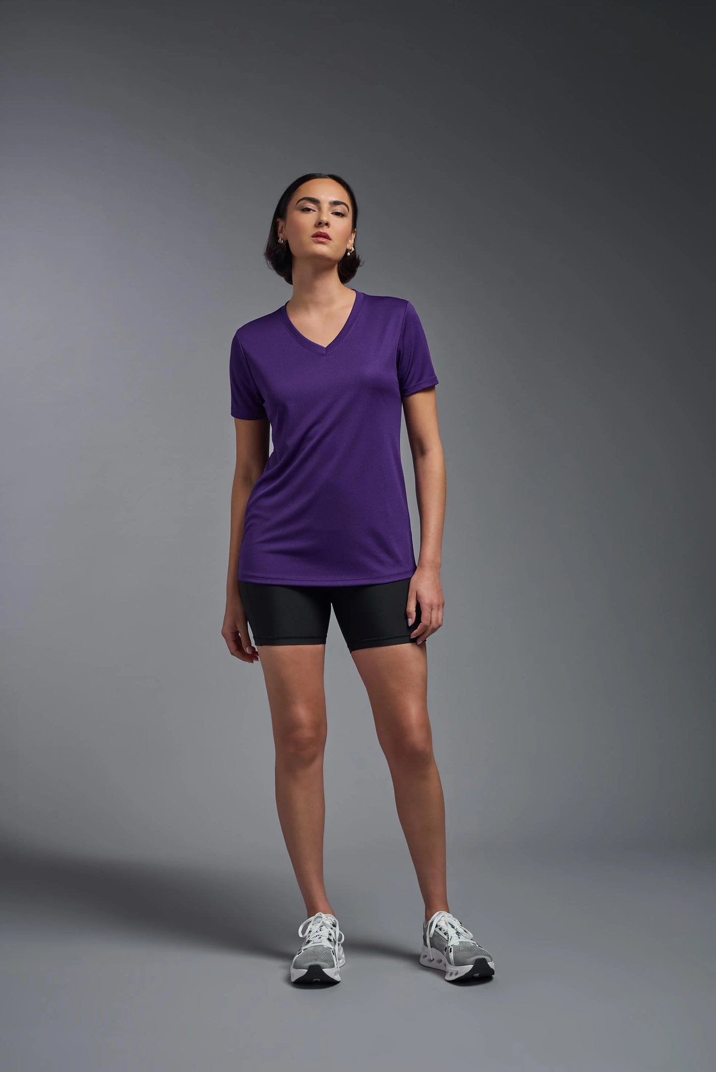 Person wearing a purple shirt and black shorts on a gray background