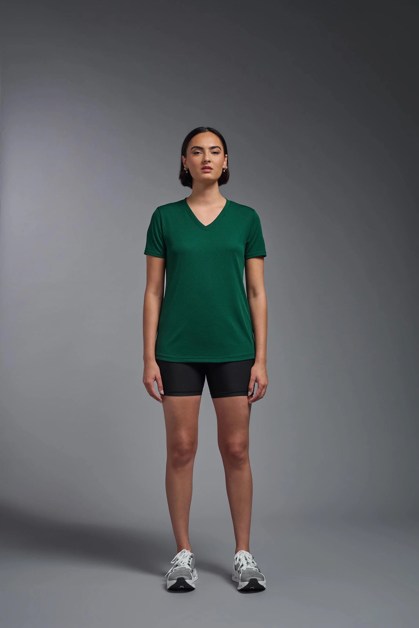 Person wearing a green t-shirt and black shorts on a gray background