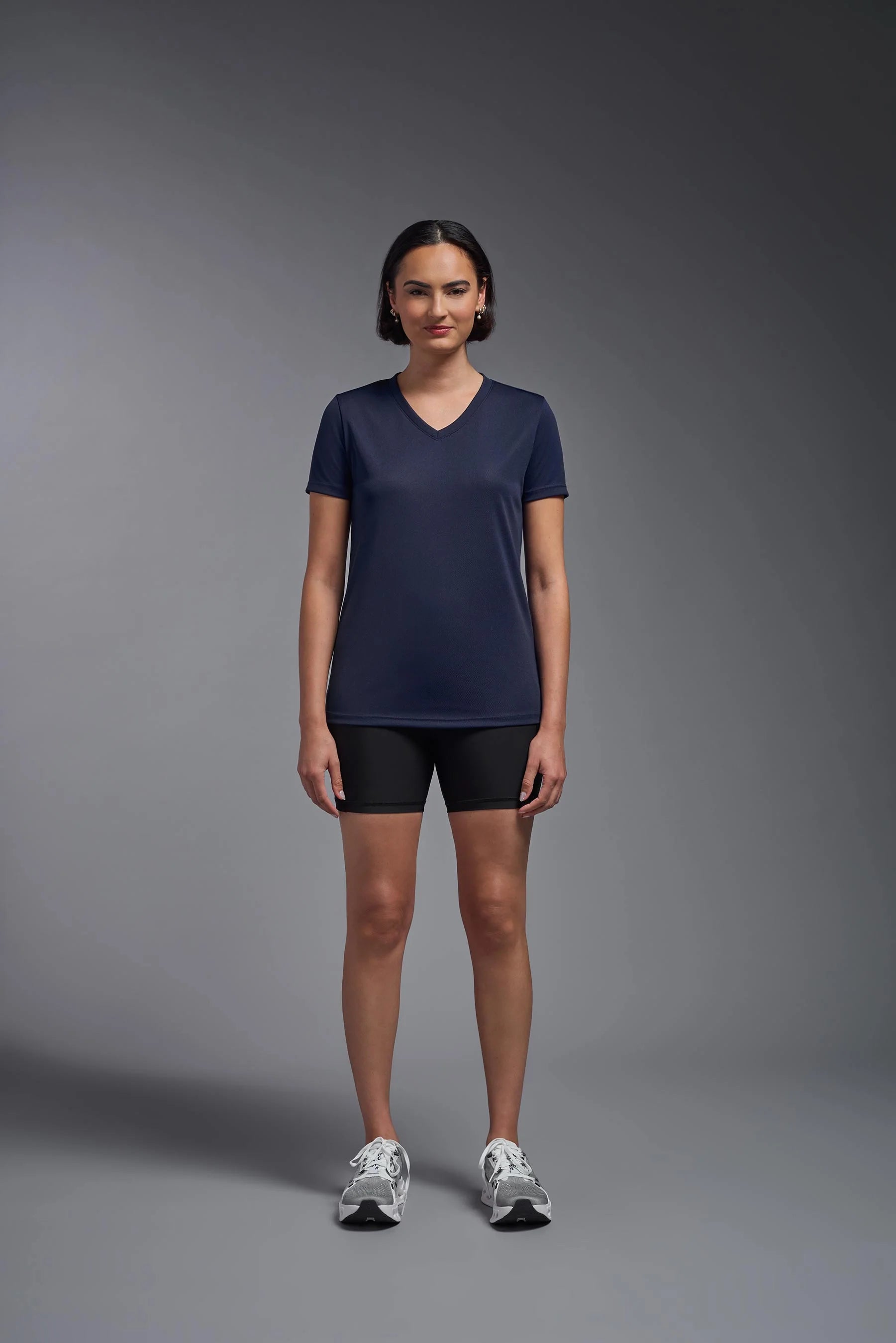 Woman wearing a navy blue t-shirt and black shorts on a gray background