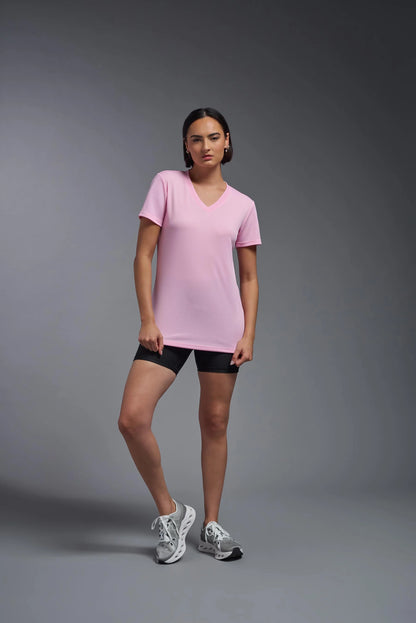 Woman wearing a pink t-shirt and black shorts on a gray background