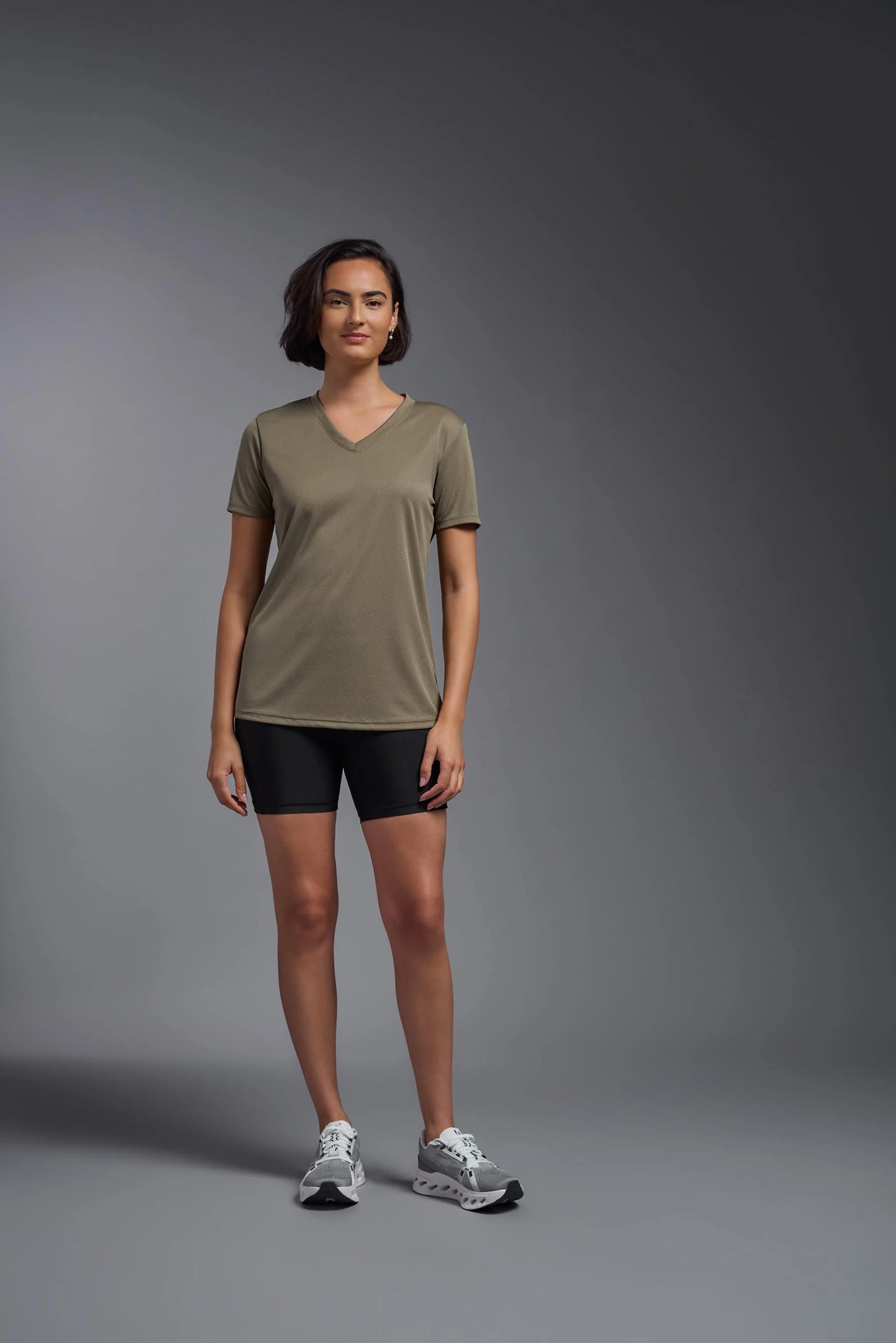 Woman wearing a green t-shirt and black shorts on a gray background