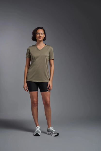 Woman wearing a green t-shirt and black shorts on a gray background