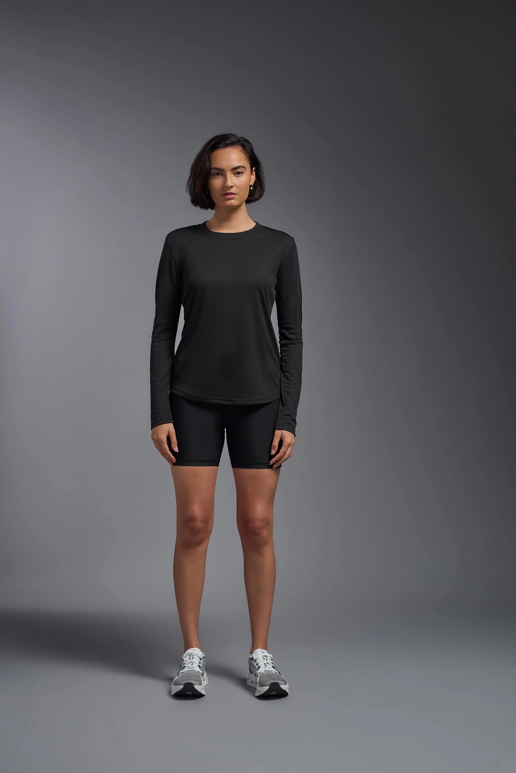 Person wearing a black long-sleeve top and shorts on a gray background