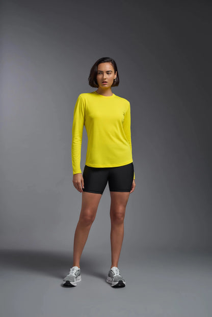 Person wearing a yellow long-sleeve shirt and black shorts on a gray background