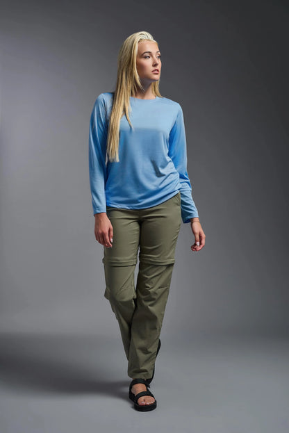 Woman wearing a blue top and green pants on a gray background