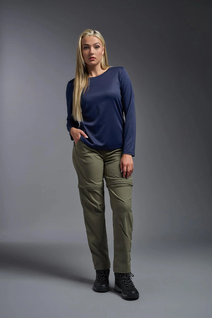 Woman wearing a navy blue top and green pants against a gray background