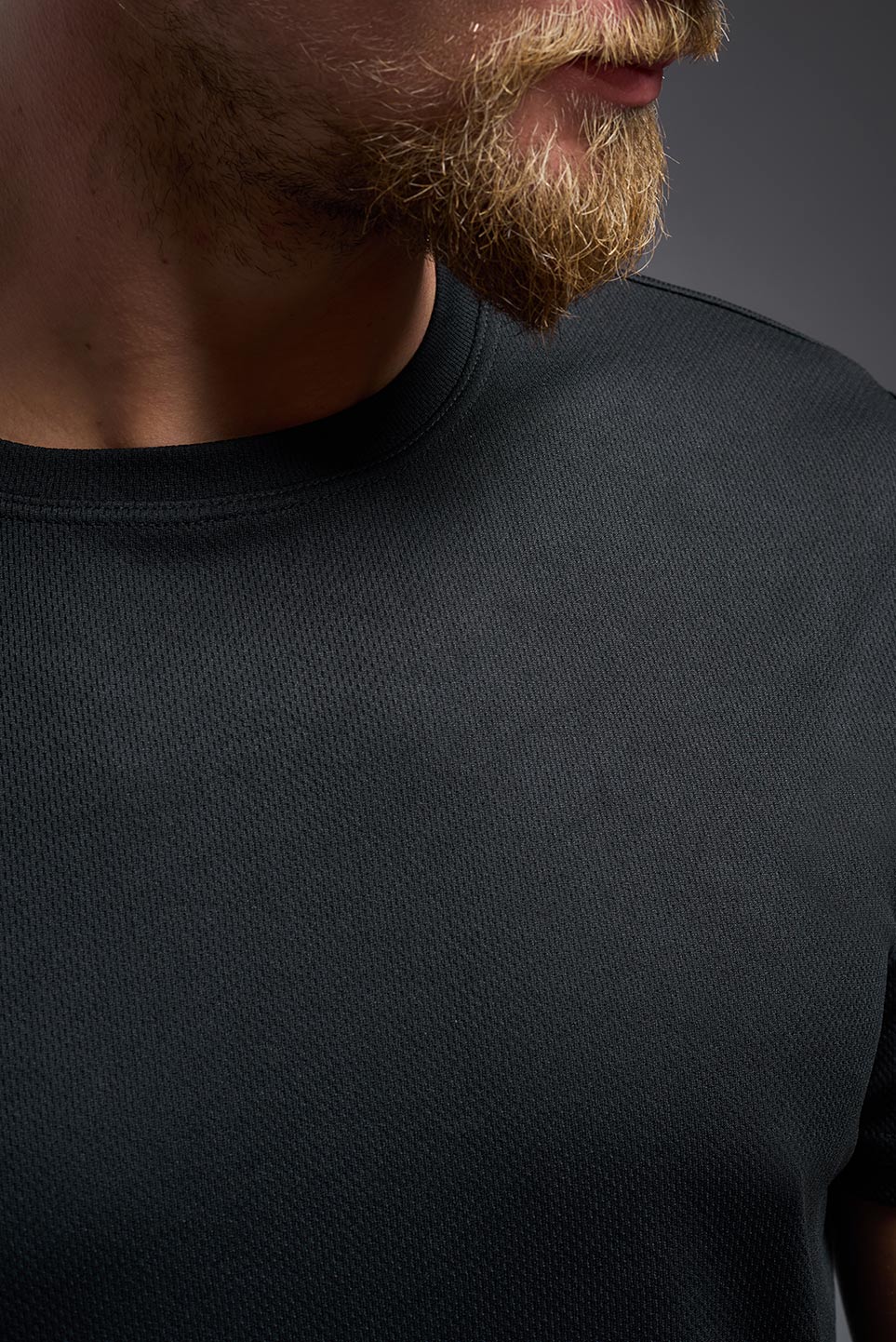 Close-up of a person wearing a black t-shirt against a dark background