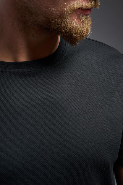 Close-up of a person wearing a black t-shirt against a dark background