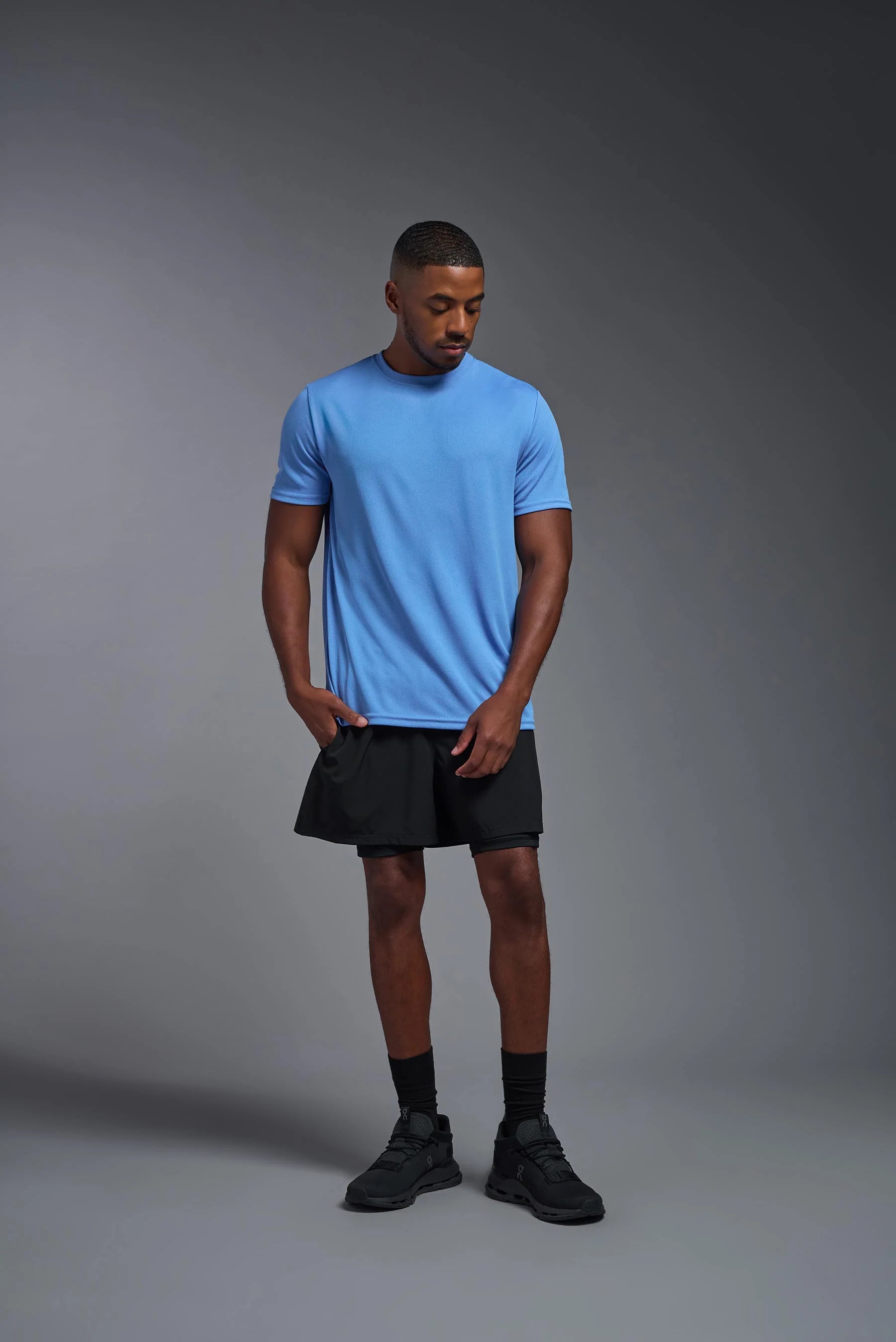 Man wearing a blue t-shirt and black shorts on a gray background