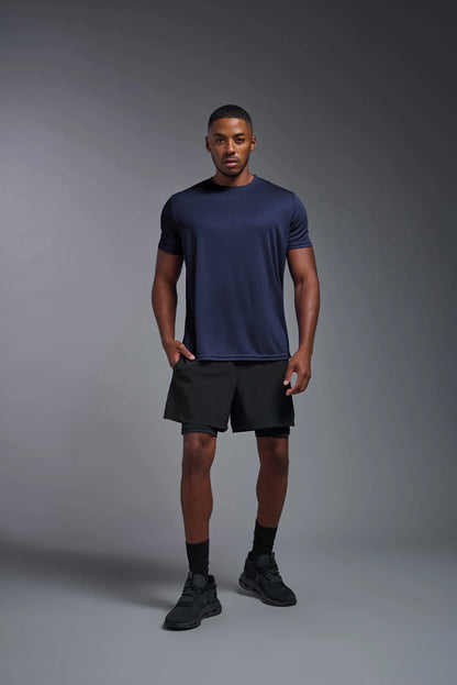 Man wearing a navy blue t-shirt and black shorts on a gray background