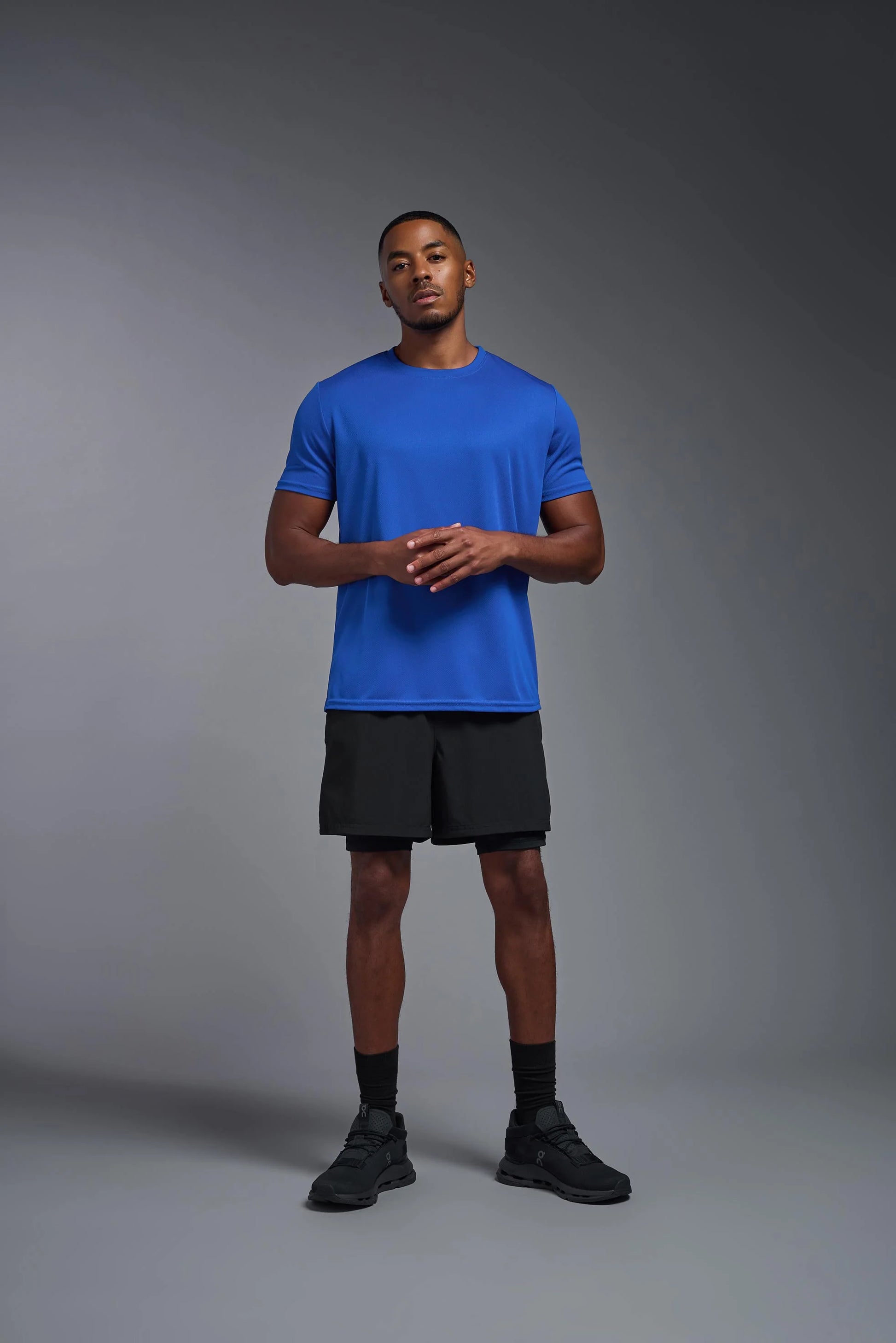 Man wearing a blue t-shirt and black shorts on a gray background