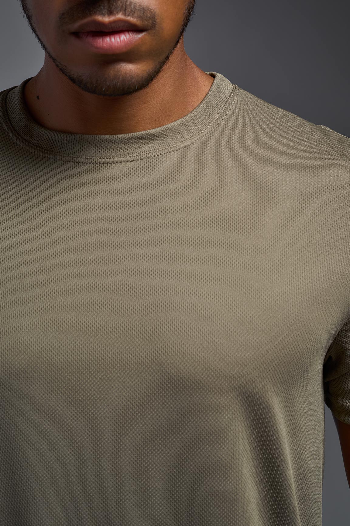Man wearing a plain olive green t-shirt against a gray background