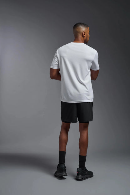 Man wearing a white t-shirt and black shorts standing against a gray background