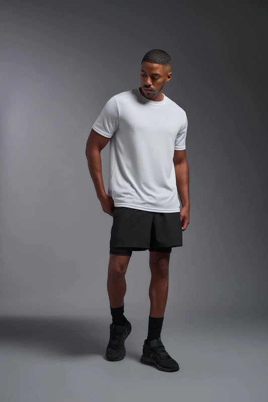 Man wearing a white t-shirt and black shorts on a gray background
