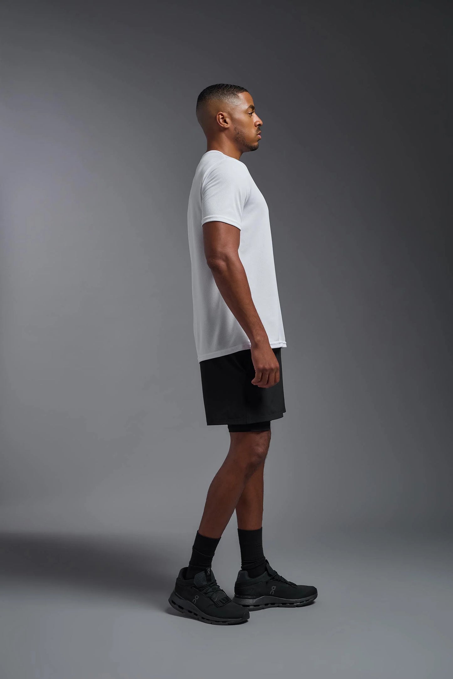 Man wearing a white t-shirt and black shorts on a gray background