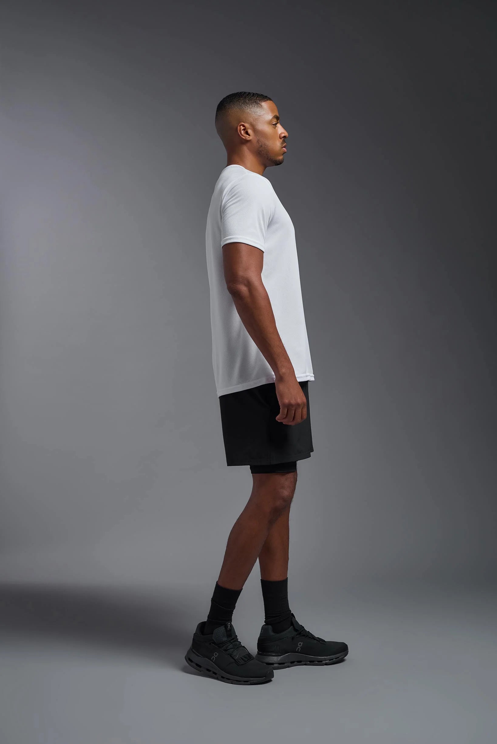 Man wearing a white t-shirt and black shorts on a gray background