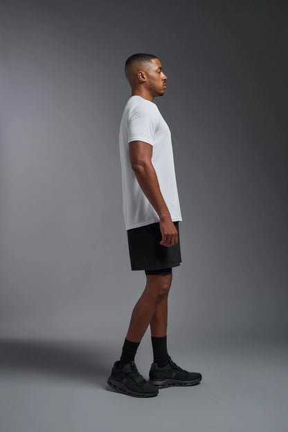 Man wearing a white t-shirt and black shorts on a gray background