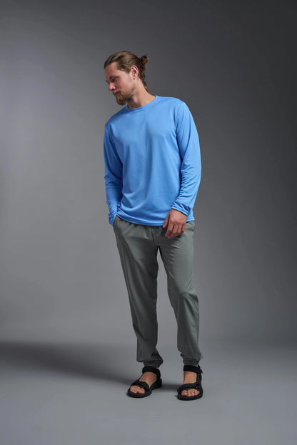 Man wearing a blue long-sleeve shirt and gray pants on a gray background