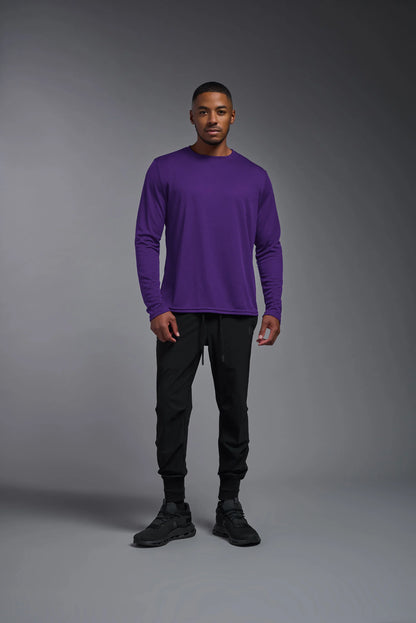 Man wearing a purple long-sleeve shirt and black pants against a gray background