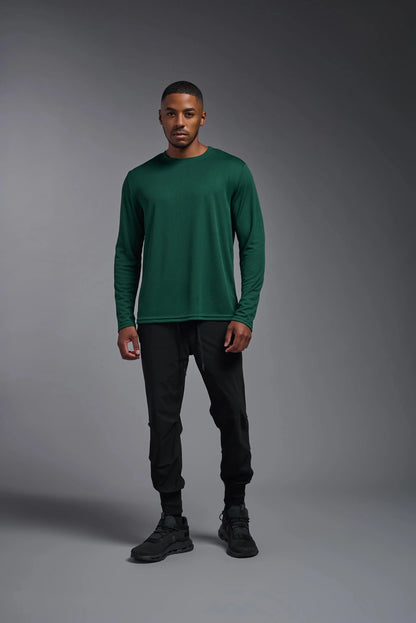 Man wearing a green long-sleeve shirt and black pants against a gray background