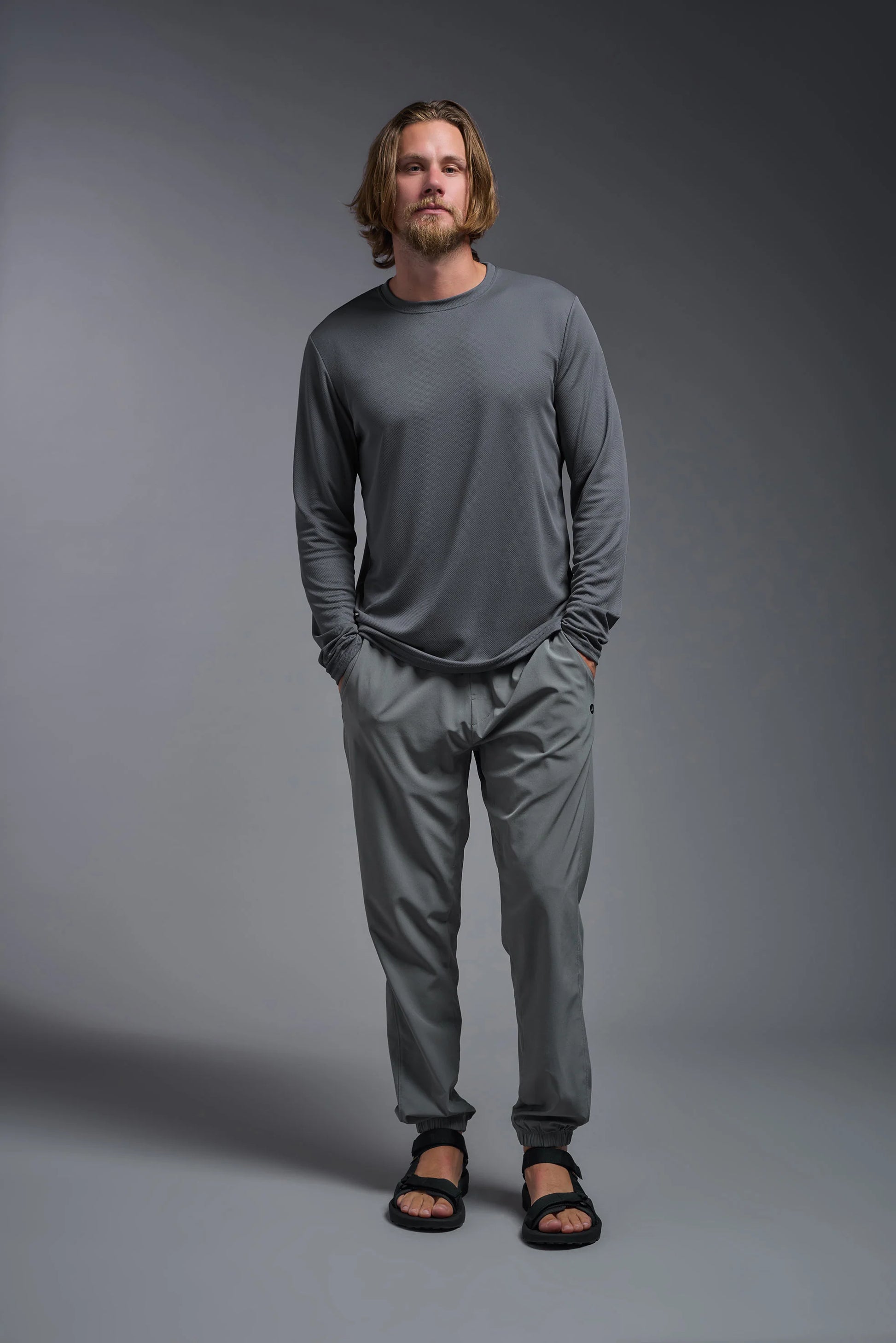 Man wearing a gray long-sleeve shirt and pants against a gray background