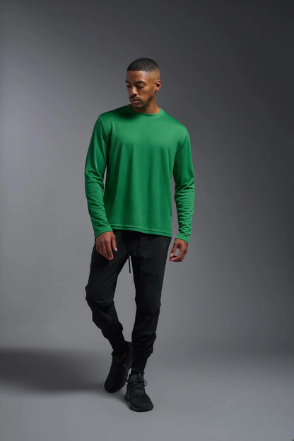 Man wearing a green long-sleeve shirt and black pants on a gray background