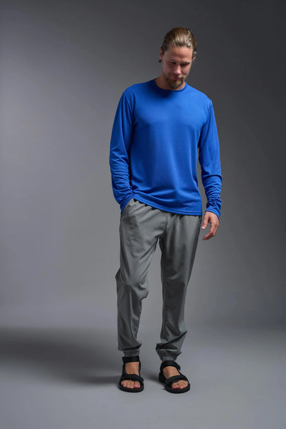 Man wearing a blue long-sleeve shirt and gray pants on a gray background