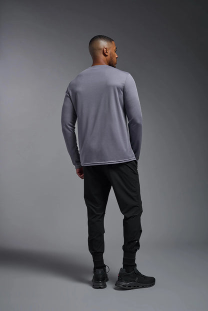 Person wearing a gray long-sleeve shirt and black pants on a gray background