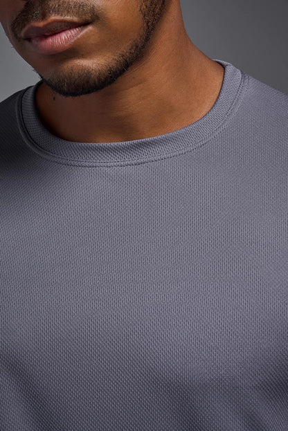 Close-up of a person wearing a gray sweatshirt with a neutral background