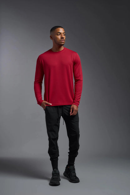 Man wearing a red long-sleeve shirt and black pants against a gray background