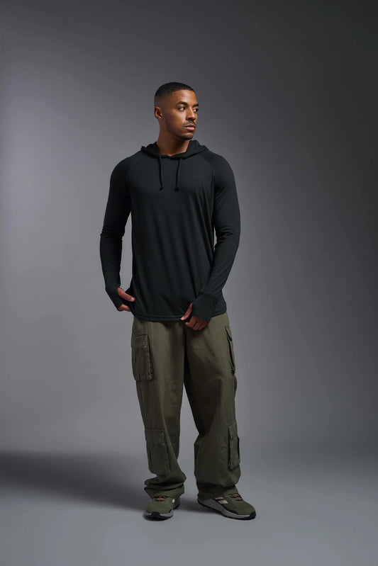 Man wearing a black hoodie and green cargo pants on a gray background