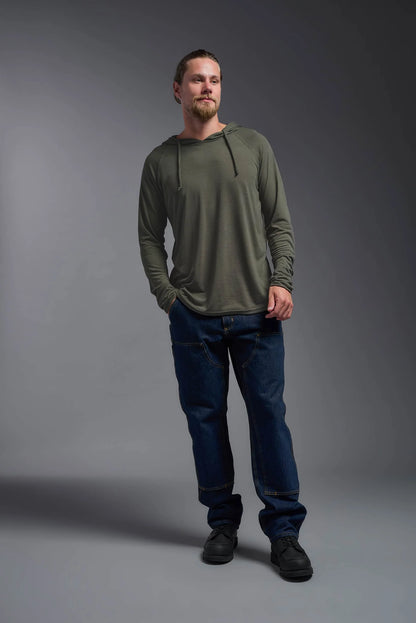 Man wearing a green hoodie and blue jeans standing against a gray background