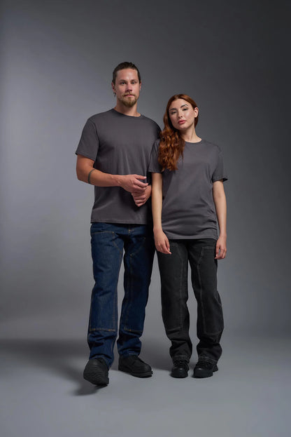 Two people wearing gray t-shirts and dark pants standing against a gray background