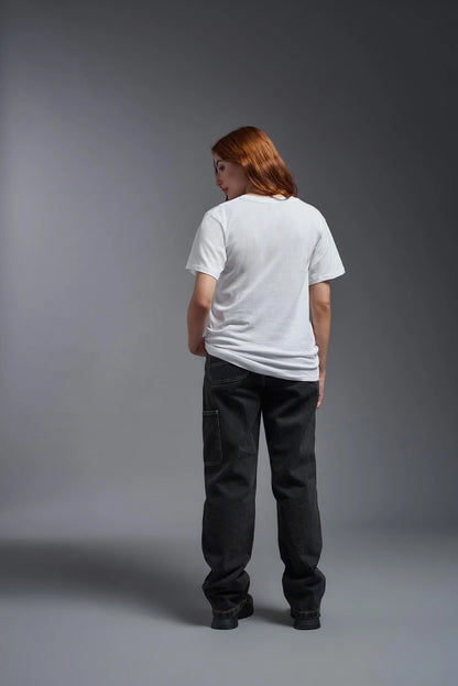 Person wearing a white t-shirt and dark pants against a gray background
