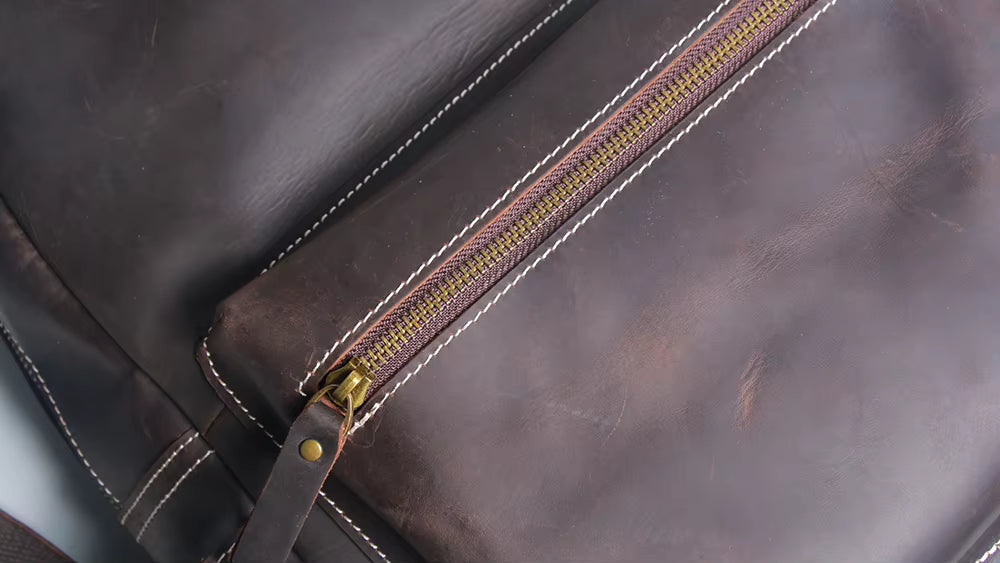 Close-up of a brown leather bag with a gold zipper.