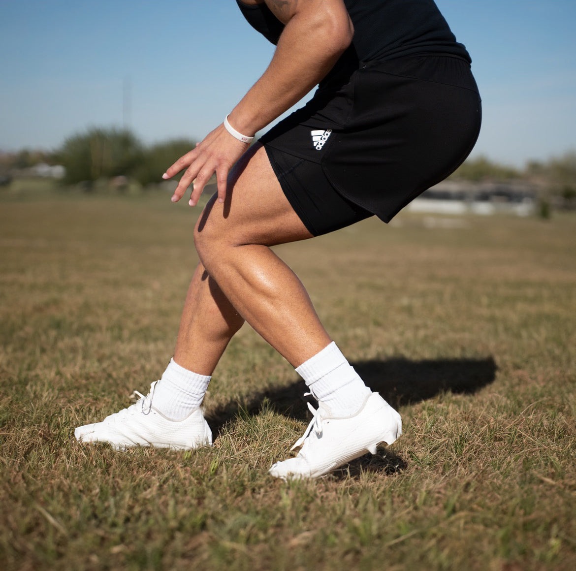 Person wearing black athletic shorts and white sneakers on a grassy field