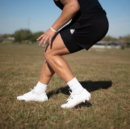 Person wearing black athletic shorts and white sneakers on a grassy field