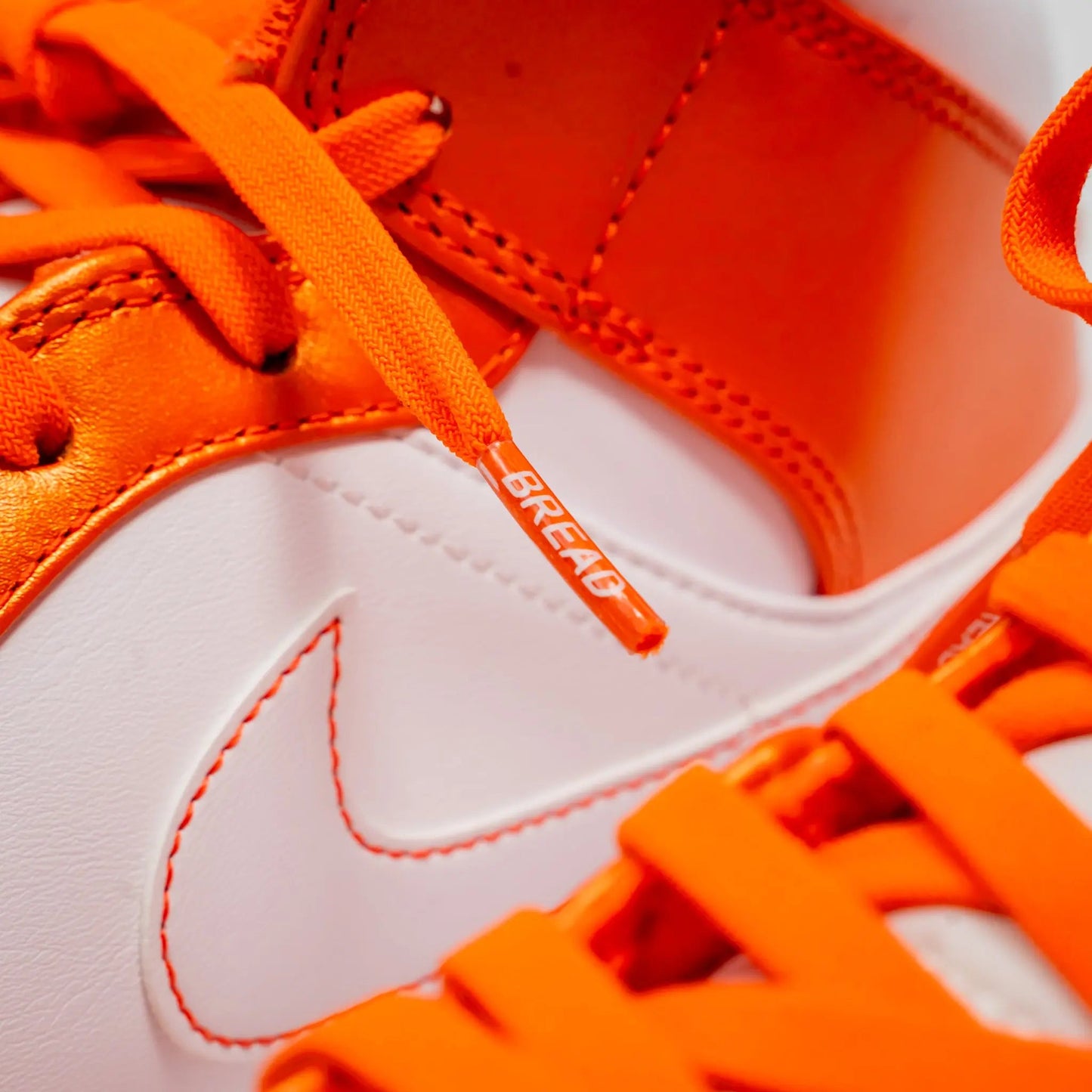 Close-up of orange and white sneakers with a visible brand logo.