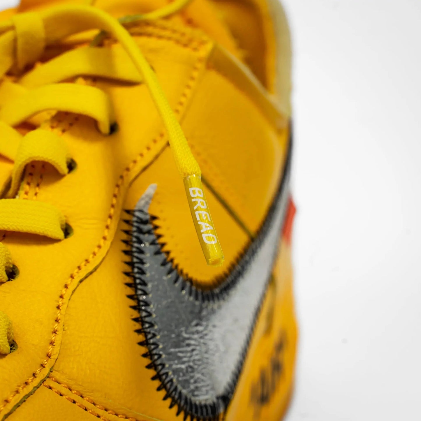 Yellow sneaker with a visible brand logo on a white background
