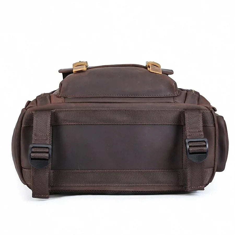 Dark brown leather camera backpack rear view with wide strap and metal buckle accents
